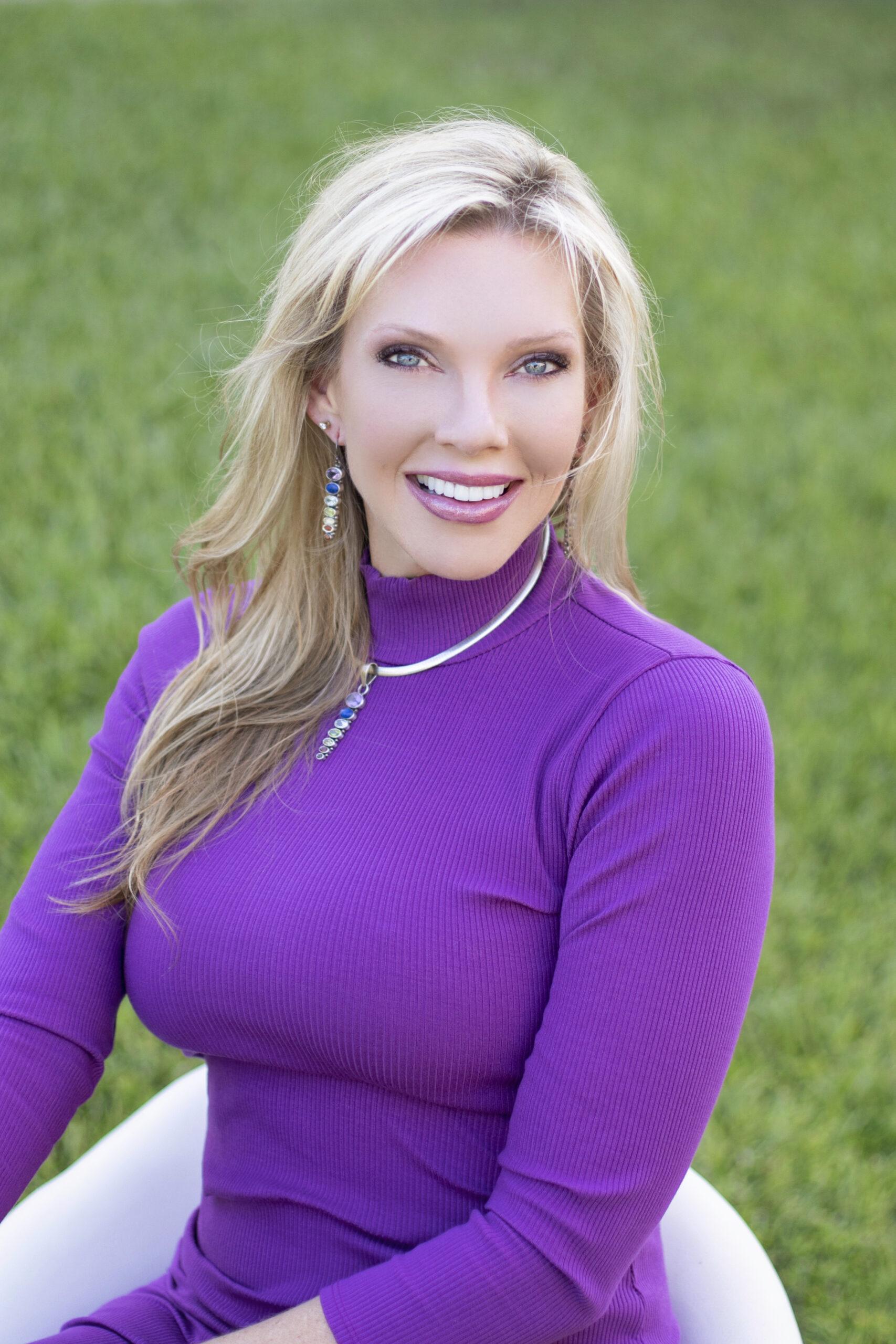 Woman in purple top smiling outdoors.